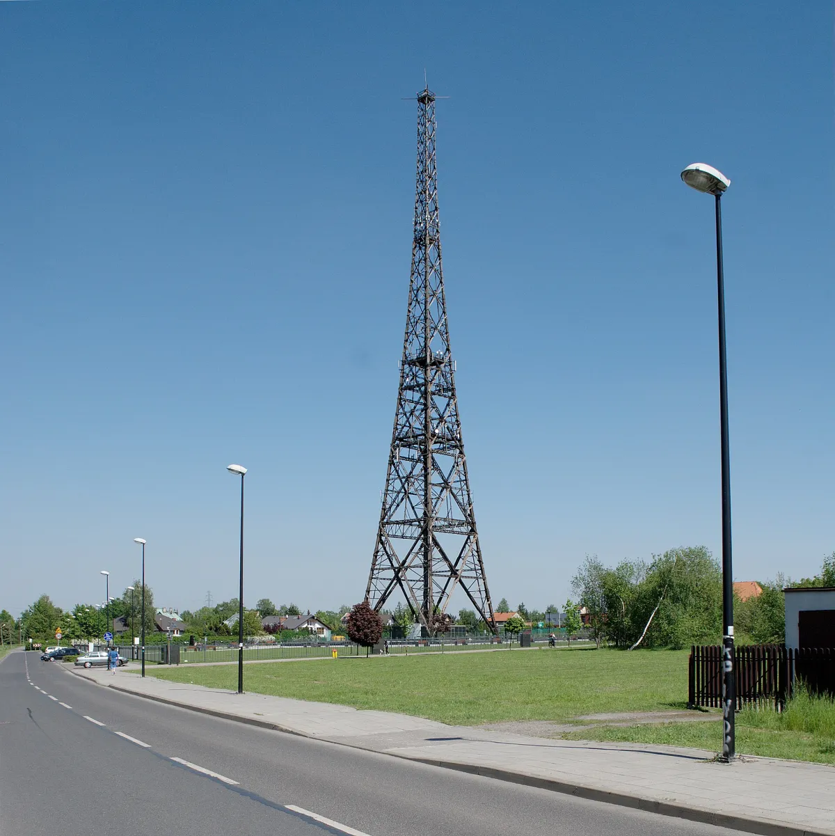 The Gliwice radio tower, a tall latticed wooden transmission mast, seen from a road in daylight.