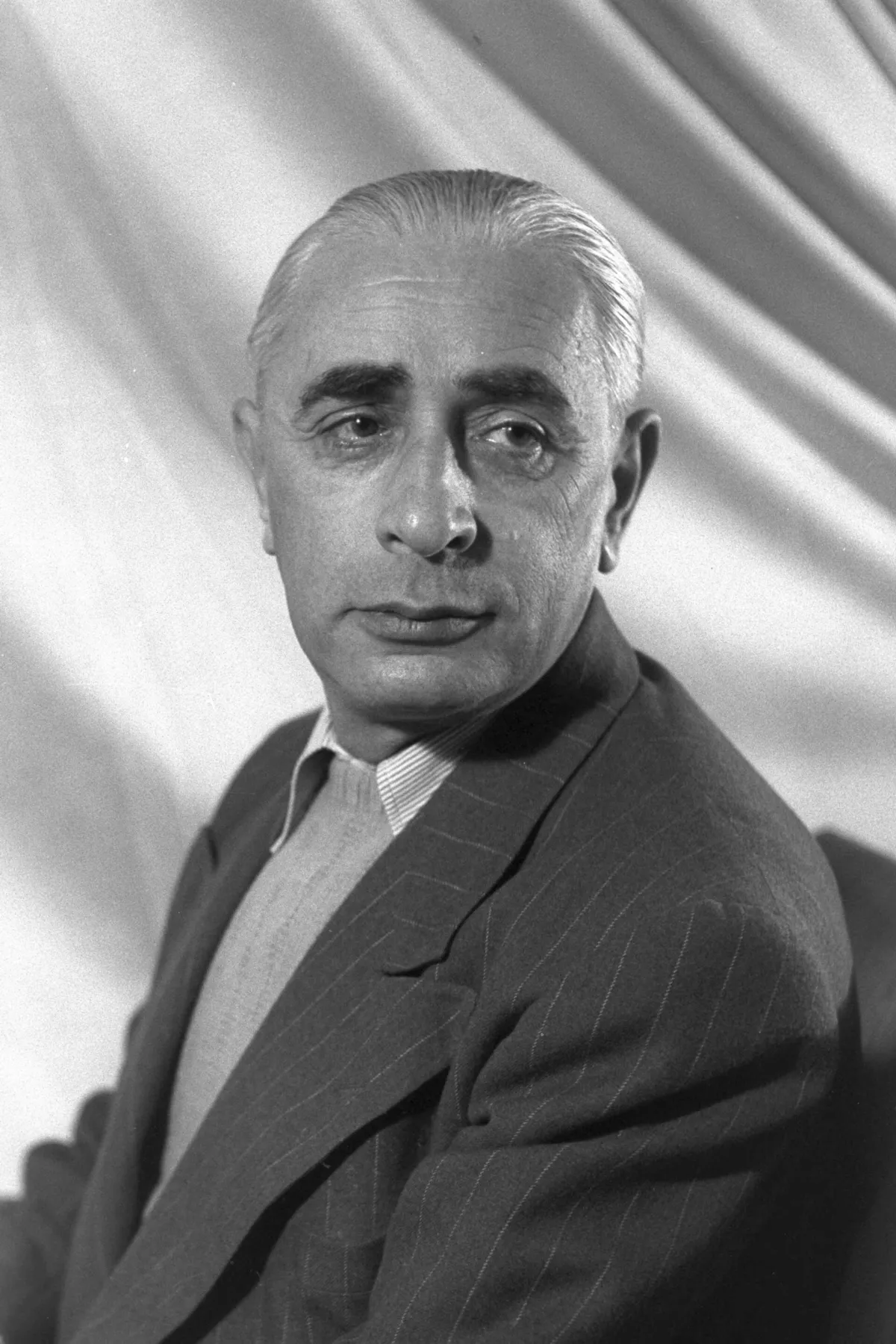 Pinhas Lavon in a studio portrait, wearing a pinstriped suit.