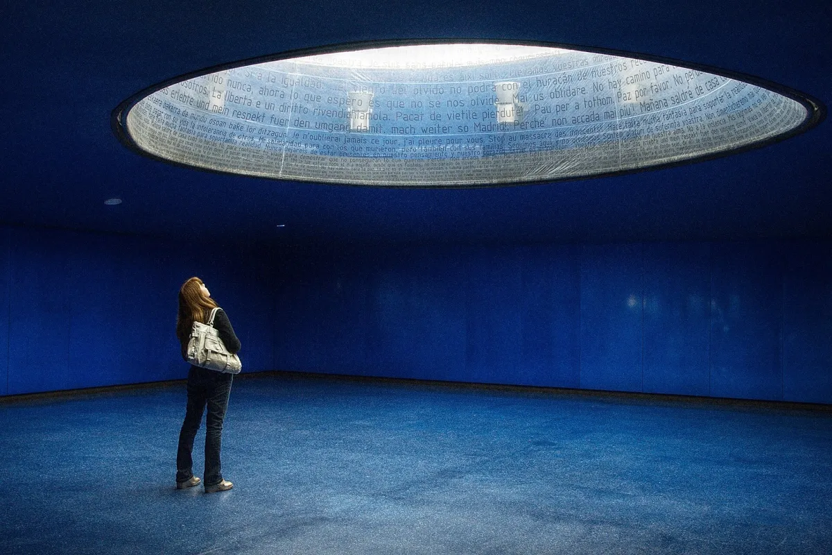 The 11-M memorial at Atocha station in Madrid: a tall translucent glass cylinder rising above the concourse.