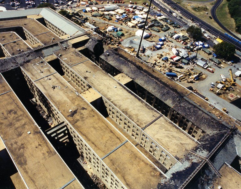 Aerial view along the roofline of the damaged section, with the response area beyond.