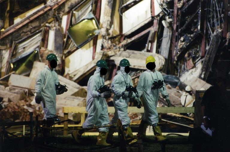 Four workers in protective suits and hard hats crossing the site at night.
