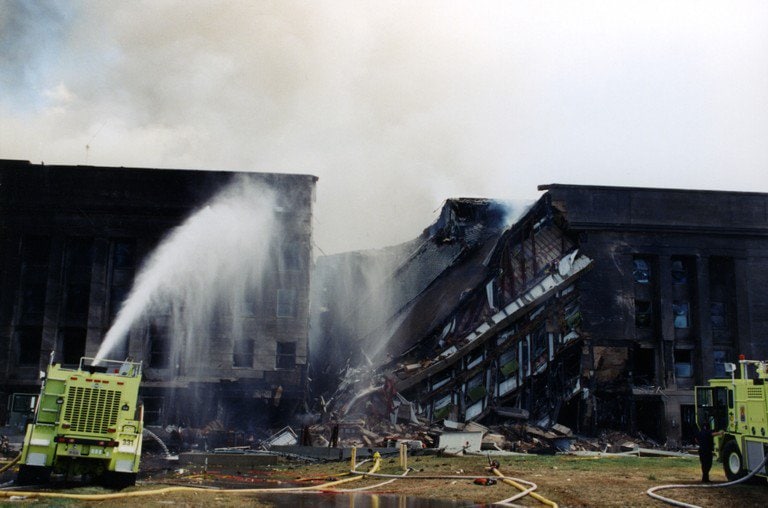 Fire crews directing water onto the collapsed section of the facade.