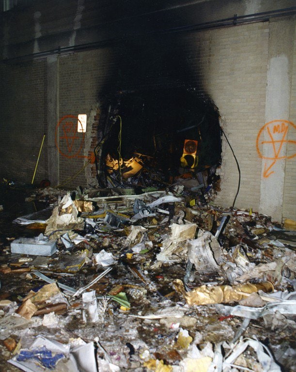 A blackened breach in the exterior wall, debris piled across the foreground.